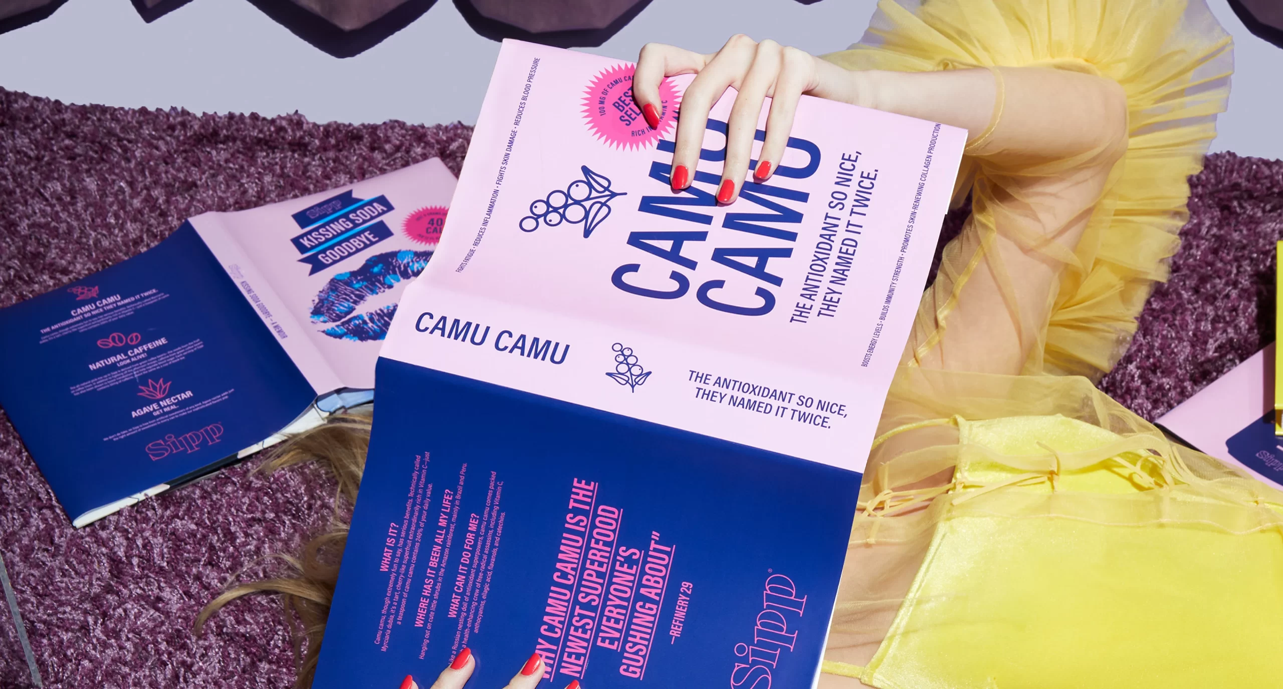 Woman with red nails reading a colorful book about the Sipp antioxidant Camu Camu