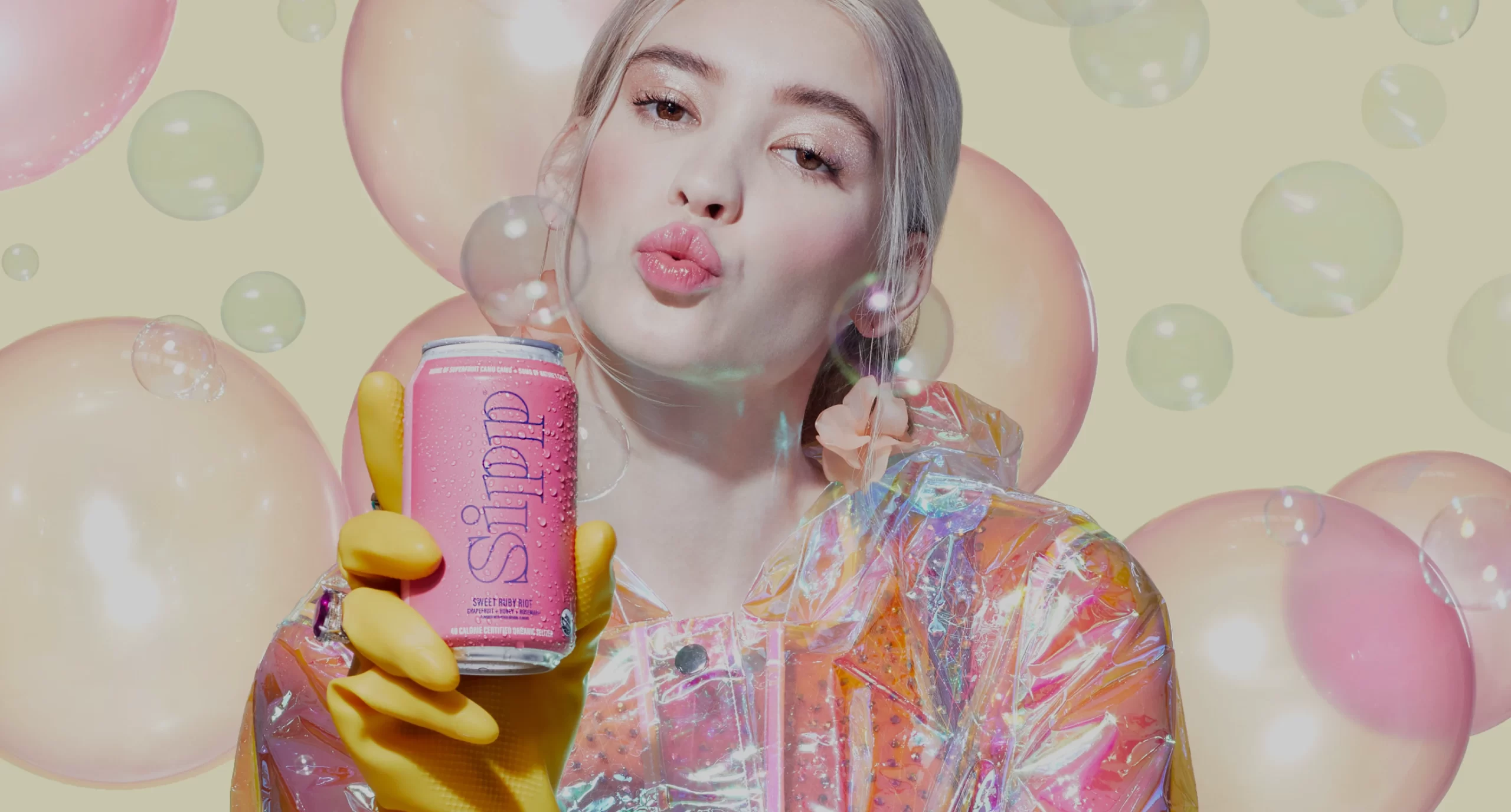 Woman holding pink can of camu camu flavor Sipp surrounded by bubbles